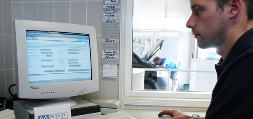 mechanic on using MOT system on computer at an MOT test station