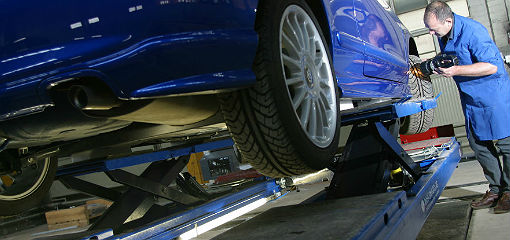 mechanic inspecting tyre of vehicle on inspection ramp