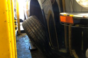 A photo of a car where the wheel is leaning away from the vehicle, indicating it's partially detached.