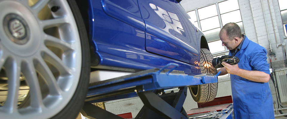 MOT tester inspecting blue car