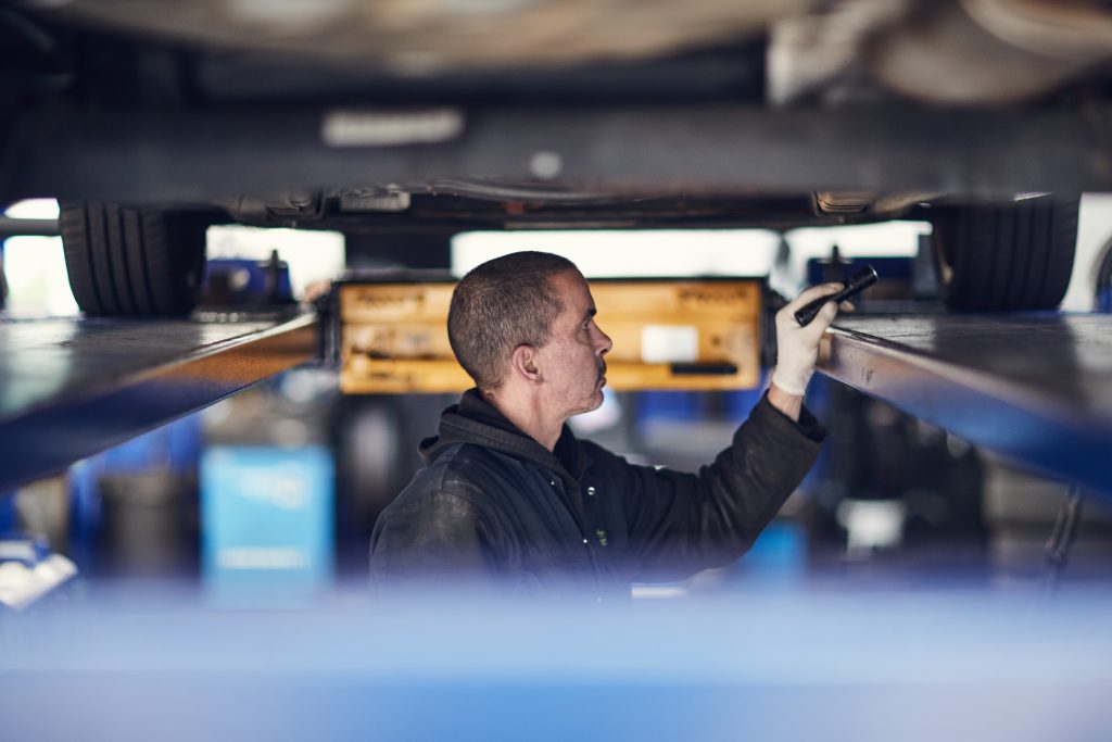 MOT tester checking the underneath of a car